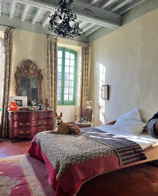 Bedroom with vintage furniture, patterned curtains, and a dog lying on the bed