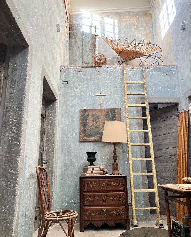 Vintage bathroom with a pedestal sink, oval mirror, wicker hamper, and framed art on the wall