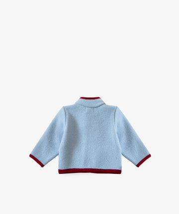 The Austrian Wool Jacket is a light blue, long-sleeve merino wool jacket with maroon trim on the collar, cuffs, and hem, inspired by traditional Austrian children’s jackets and shown against a plain white background.