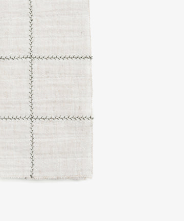 The Filial Check Napkin, Set of 6, features light beige fabric with a dark branch stitch grid pattern—ideal for enhancing any tabletop setting.