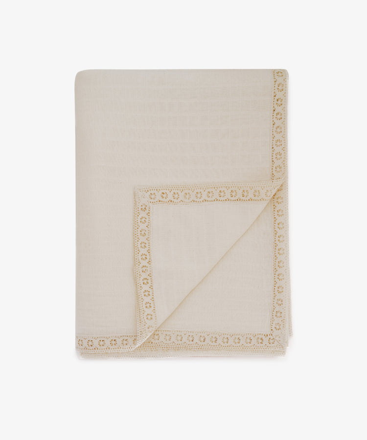 The Double Gauze Flower Tablecloth is a cream-colored, folded cloth with decorative lace trim along the edges, resembling a soft and airy blanket, displayed against a white background.