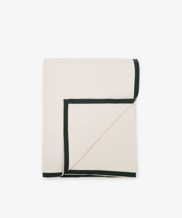 A white folded tablecloth featuring a decorative green trim along the edges.