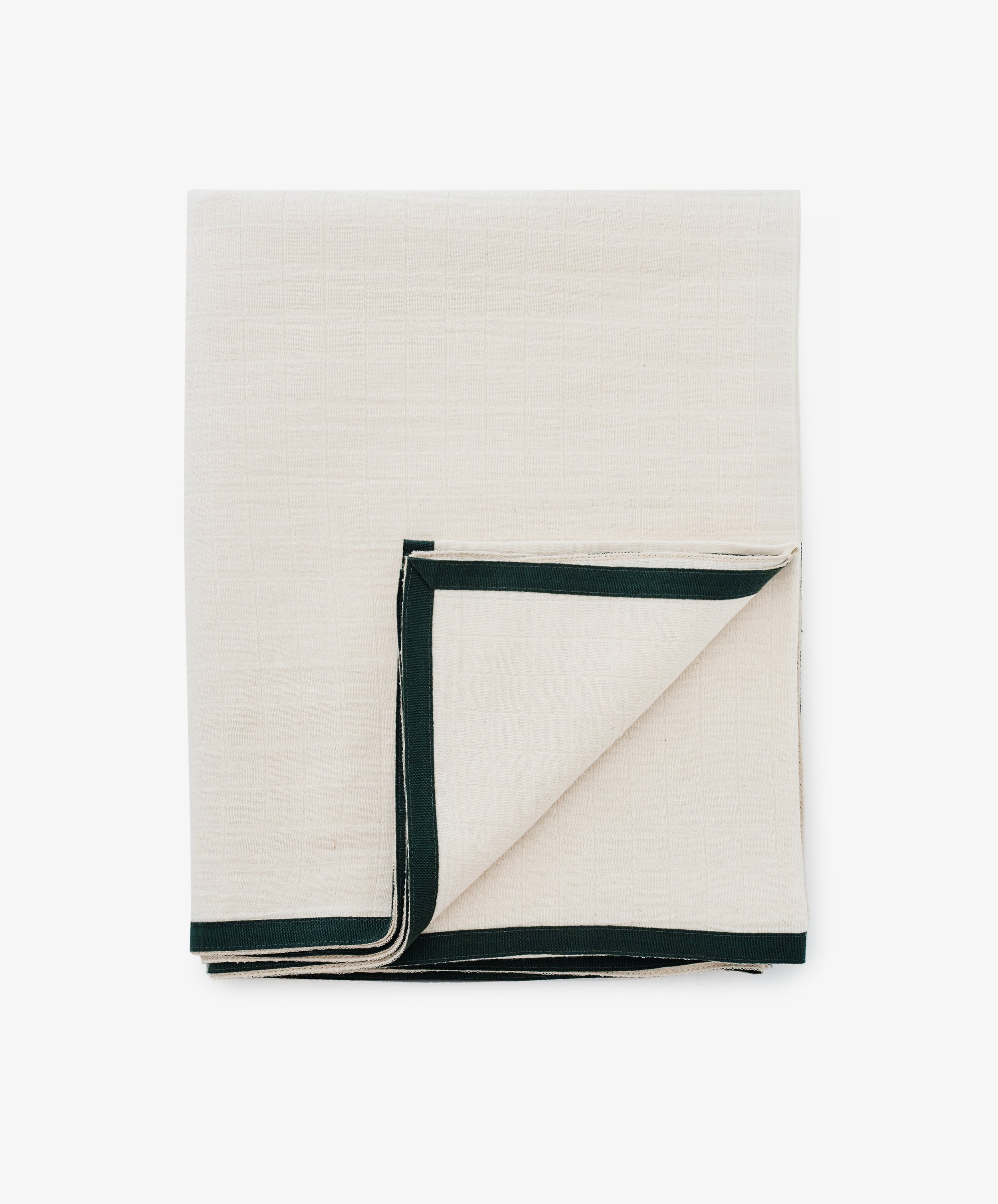 The Fita Tablecloth, made from natural cotton, features a folded beige design with a dark green border and is displayed flat on a white surface to highlight its organic texture.