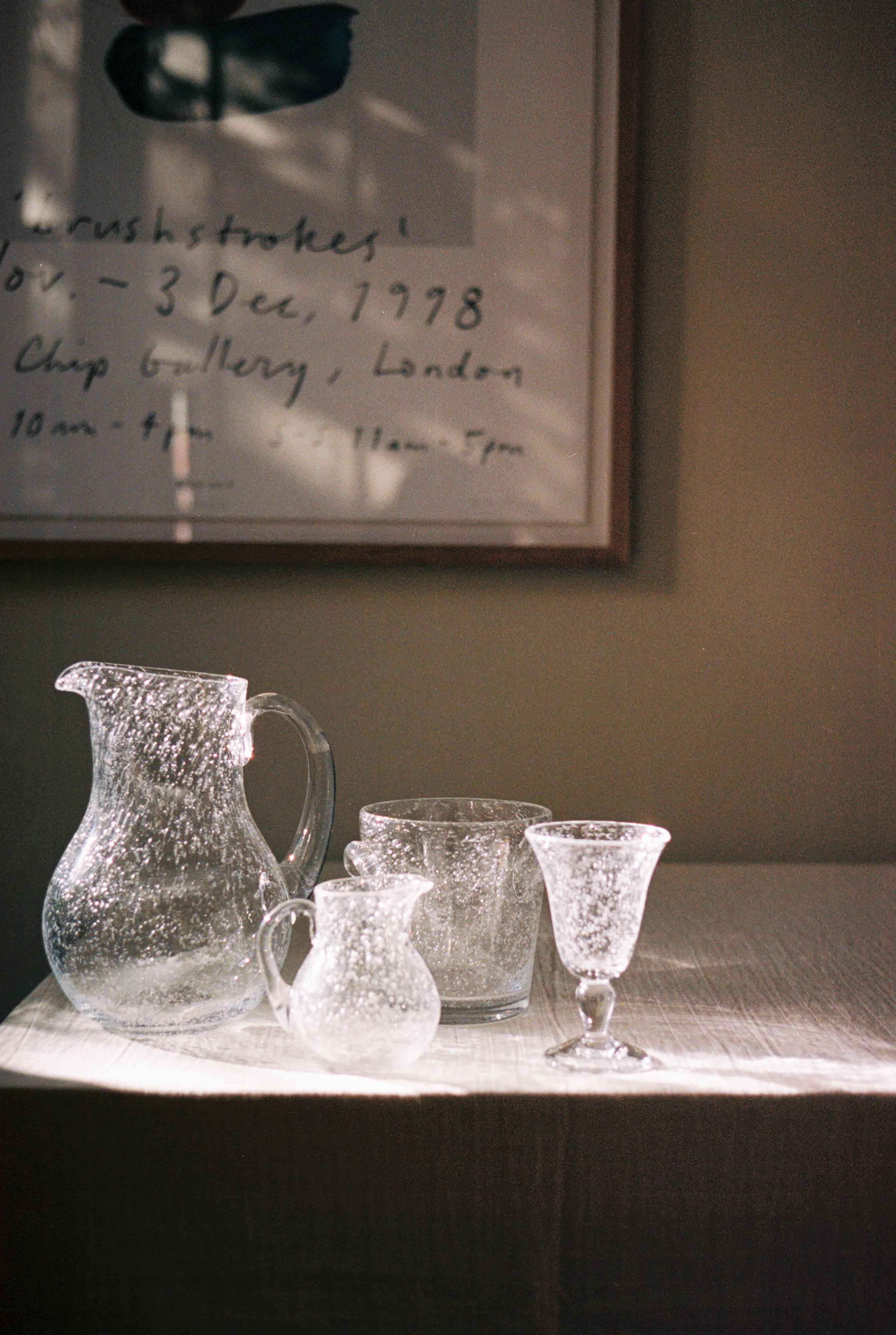 Lauren Water Jug in situ with other bubble glass pieces on wooden table.