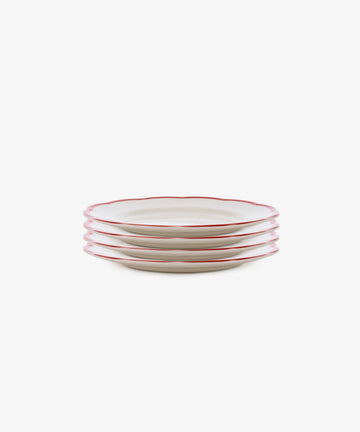 A set of four white Italian ceramic Petalo Small Plate, Set of 4 with scalloped edges and red rims, inspired by Bitossi Home, shown on a white background.