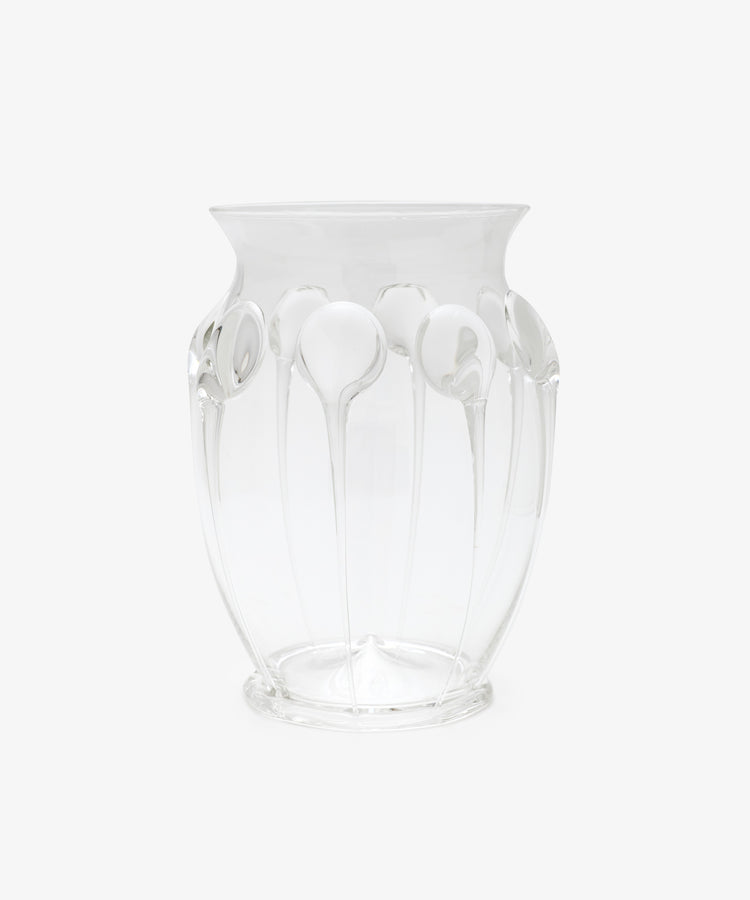 The Carlotta Vase is a clear, mouth-blown piece with a flared rim and vertical embossed patterns, set against a plain white background and highlighting Bohemian artistry.