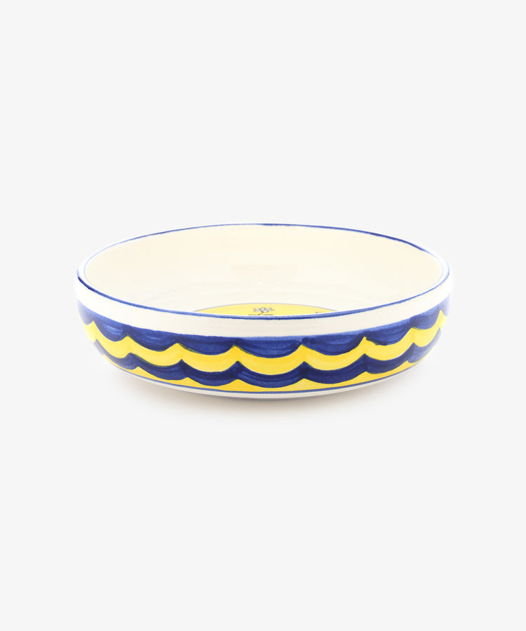 Palio Pasta Bowl in white glazed ceramic with blue and yellow accents and tortoise motif, side view.