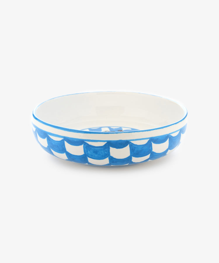 Palio Pasta Bowl in white glazed ceramic with blue accents and tower and fish motif, side view.