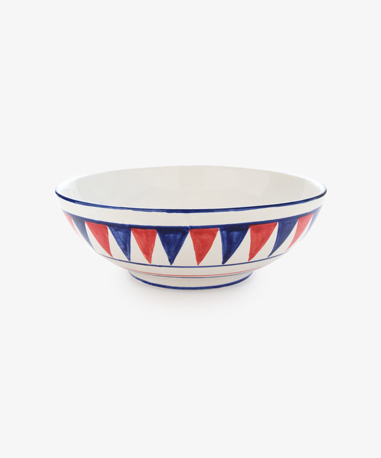 Palio Serving Bowl. Large white glazed ceramic bowl with red and blue accents, side view.