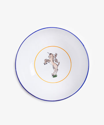 The Palio Serving Bowl, The Unicorn, is a white ceramic bowl with a thin blue rim and a central yellow circle showcasing a rearing unicorn, inspired by Sienas vibrant traditions and the spirit of Palio.
