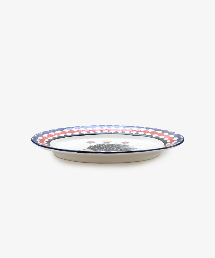 Palio Serving Platter. Glazed ceramic oval plate in red and navy designs with porcupine motif, side view.