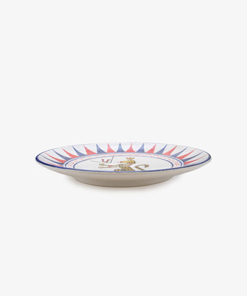 Palio Round Serving Platter. Large white glazed ceramic plate with red and blue accents, side view. 