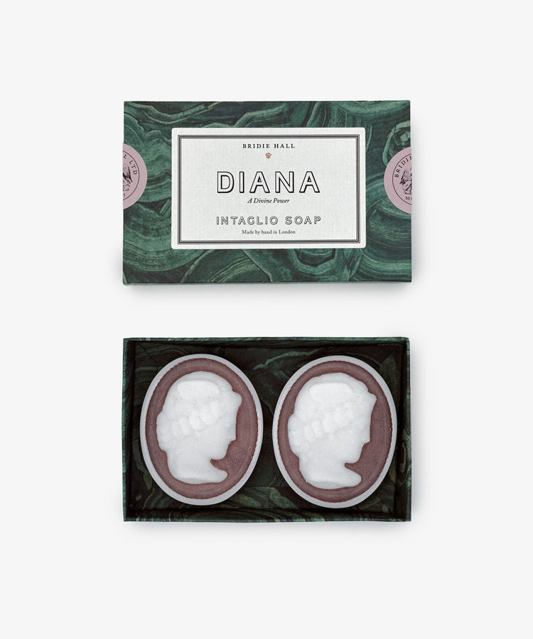 A Diana Soap, Set of 2 box holds two oval soaps, each intaglio-carved with white cameo profiles on a dark base and delicately scented with cardamom mimosa fragrance.