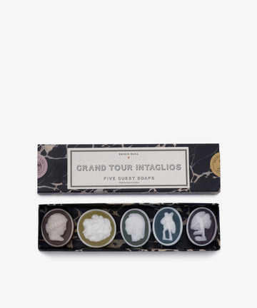 An open rectangular box labeled Grand Tour Collection of Intaglio Soaps, Set of 5 displays five round soaps, each with a unique classical cameo design, hand-poured in London for timeless elegance.