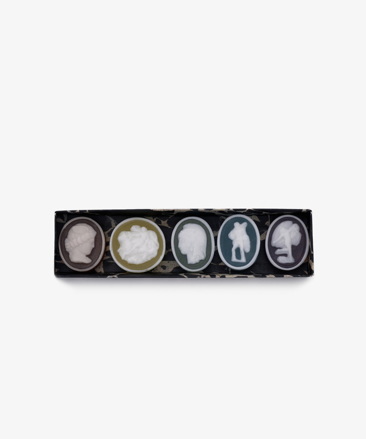 The Grand Tour Collection of Intaglio Soaps is a rectangular box with five oval soaps, each hand-poured in London and featuring a unique classical cameo design and color, arranged in a row.