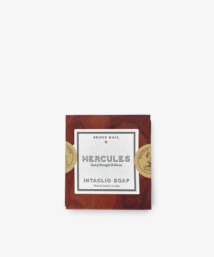 Hercules Soap features a decorative label with gold seals, sculpted design, and comes wrapped in brown paper—shown here against a white background.