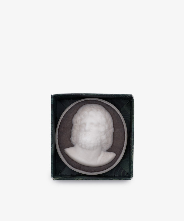 A white relief sculpture of a bearded man’s bust set in a dark round frame, displayed in a small open box—perfect as classical bathroom decor. Inspired by Hercules Soap, hand-poured in London.
