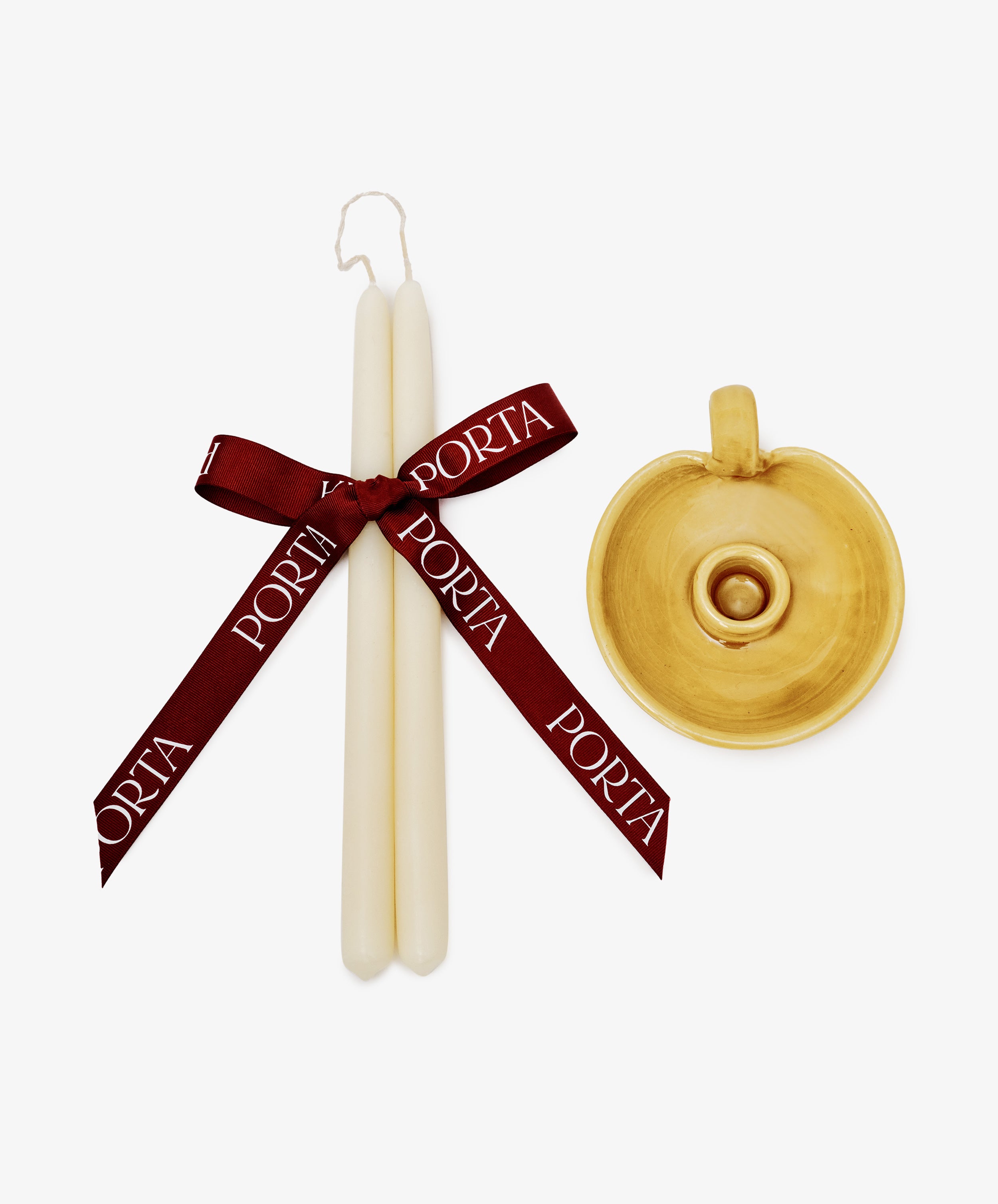 The Sparks Flying Bundle features two white tapered candles tied with a PORTA wine red ribbon beside a yellow ceramic handled candleholder, creating a charming Valentine’s Day gift set on a crisp white background.