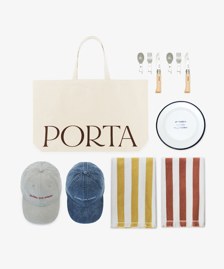 The Pesco Weekender, featuring a beige canvas tote labeled PORTA, two caps, a picnic set with metal plate and cutlery, and two striped cotton towels, is arranged on a white background.