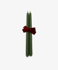 A set of two hand-dipped, mossy green Tapered Candles are tied together with a red ribbon bow and displayed against a plain white background. These elegant candles provide a long burn time, making them ideal for creating a warm and inviting atmosphere.
