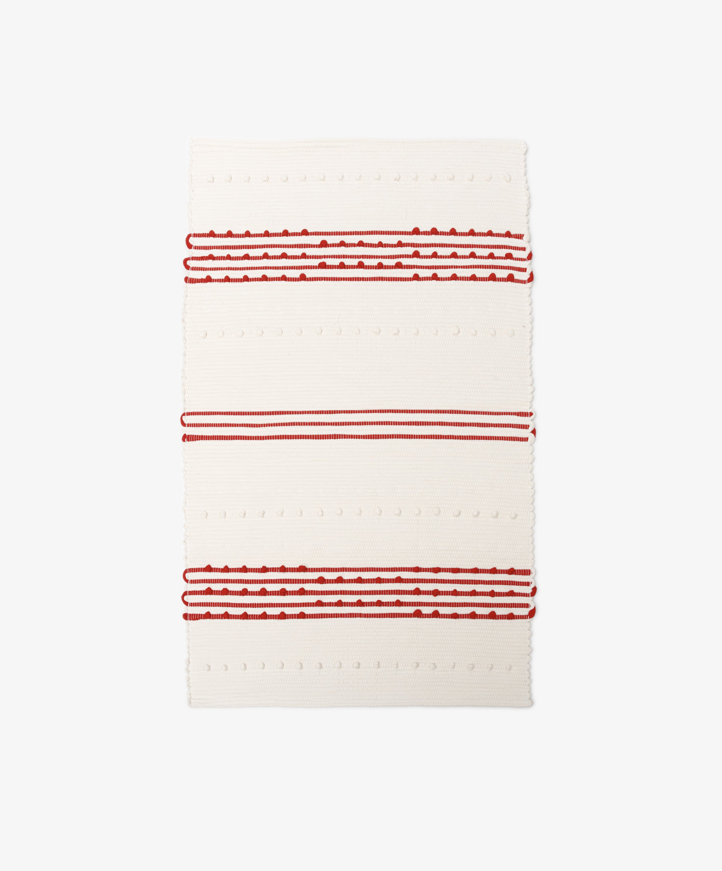 The Gaia Floor Mat is a rectangular, cream-colored rug inspired by Portuguese tradition, made from recycled fabric with textured red and white stripes and raised dot patterns.