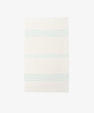 The Gaia Floor Mat is a rectangular white rug inspired by Portuguese tradition, with horizontal pale blue stripes and dotted texture—handwoven from recycled fabric for a unique look.