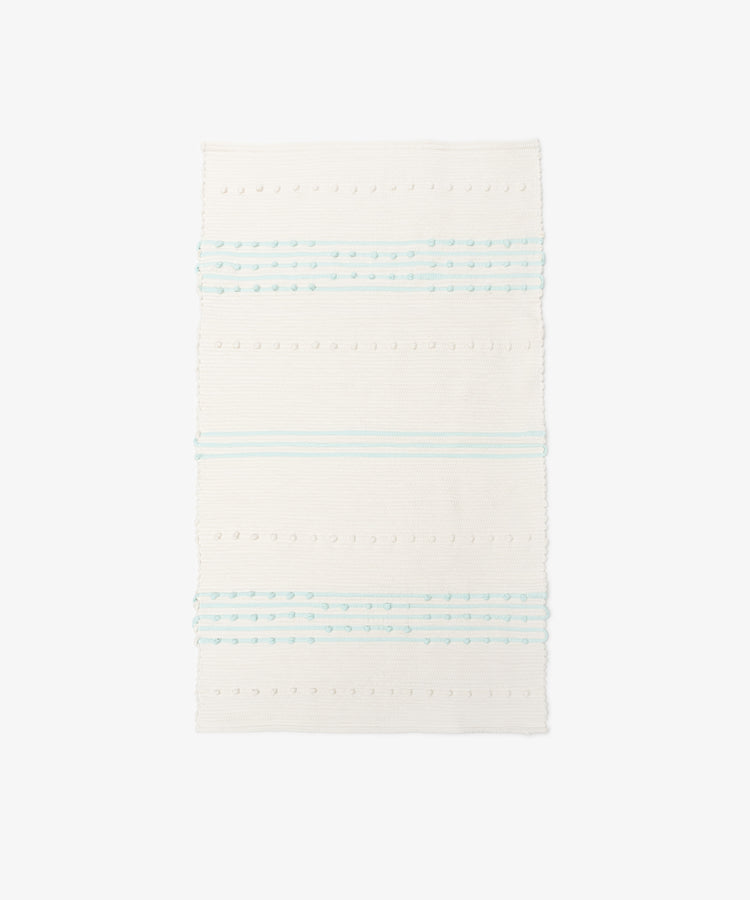 The Gaia Floor Mat is a rectangular white rug inspired by Portuguese tradition, with horizontal pale blue stripes and dotted texture—handwoven from recycled fabric for a unique look.
