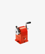 The Pencil Sharpener is a durable red manual desk tool with a black handle, shown on a plain white background.