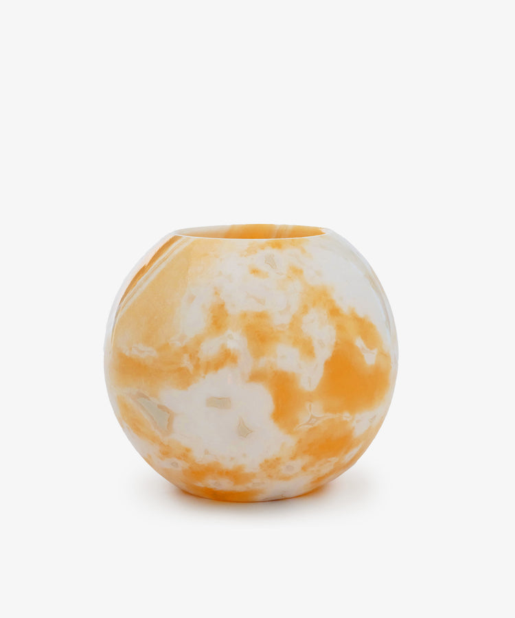 The Akila Candleholder is a round, handcrafted piece with a smooth surface, showcasing white and orange marbled patterns, displayed against a plain white background.