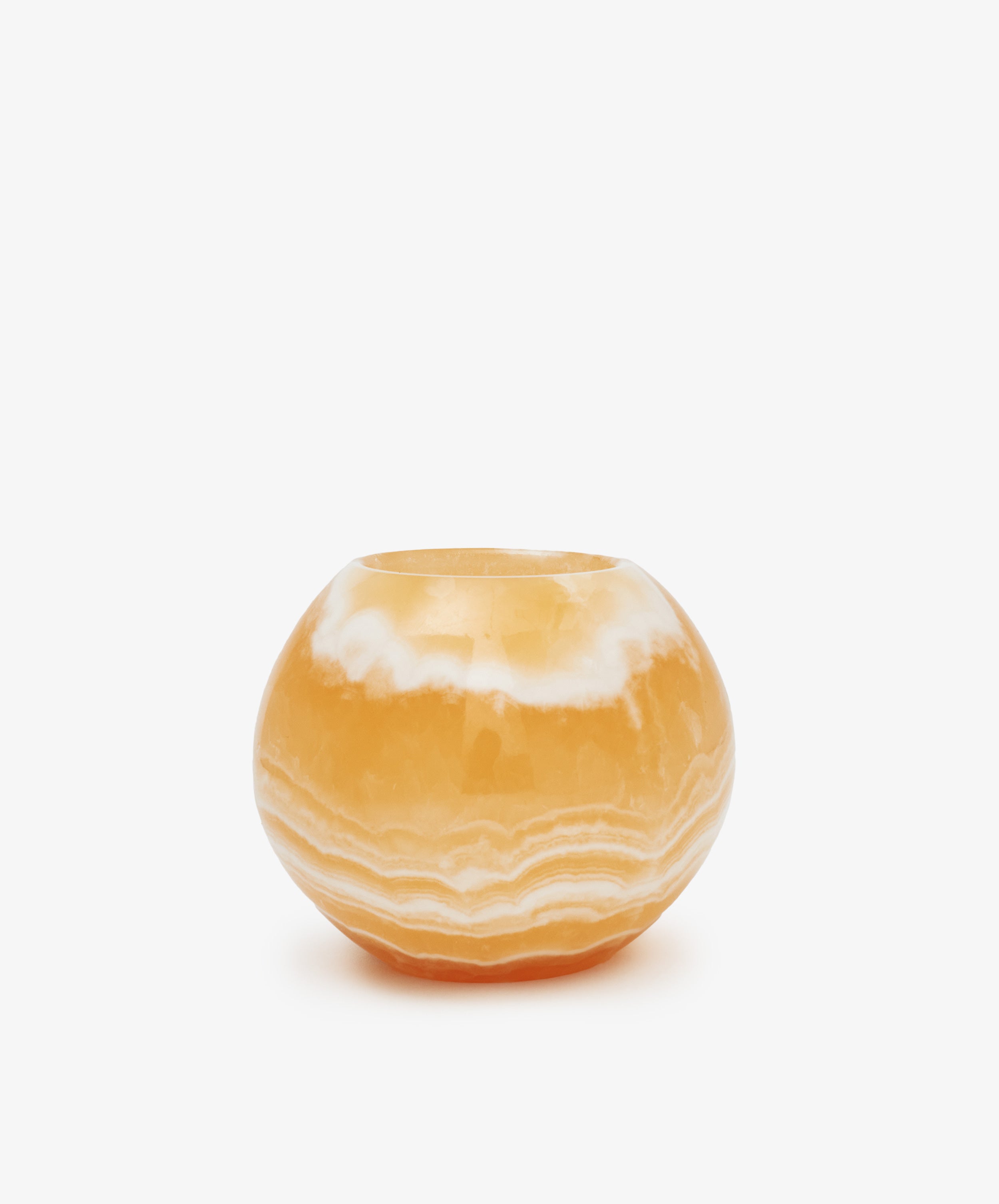 The Akila Candleholder is a round, orange onyx piece with natural white banding, handcrafted to evoke the elegance of Egyptian Alabaster, and shown on a plain white background.