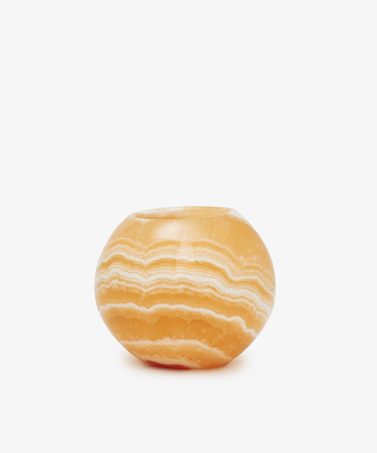 The Akila Candleholder is a round orange and white striped stone bowl with a wide opening, handcrafted from Egyptian Alabaster in Luxor. Displayed on a plain white background, it adds elegance to your home décor as a unique candle holder.