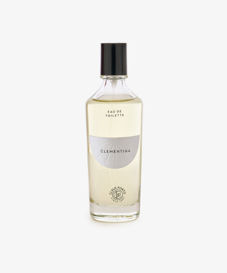 Clear glass bottle of Clementina Eau de Toilette with a black cap, white label, and light yellow liquid, featuring bergamot notes, photographed on a white background.