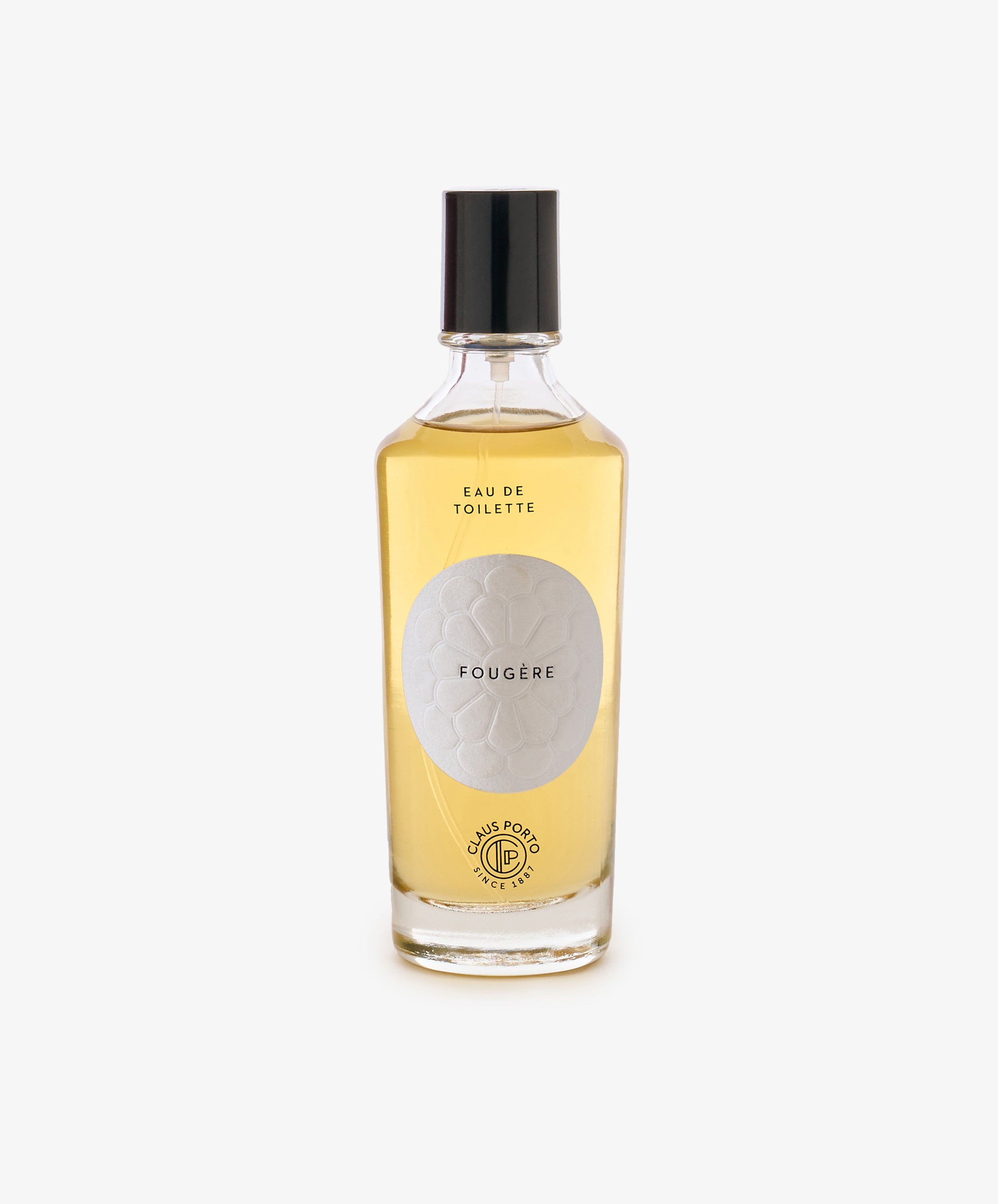A clear glass bottle with light amber liquid, black cap, and a white label reading Fougère Eau de Toilette, evoking pine needle and cedarwood notes.