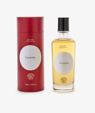 A bottle of Fougère Eau de Toilette sits beside its red cylindrical package, both with white labels and black text, evoking pine needle and cedarwood notes.