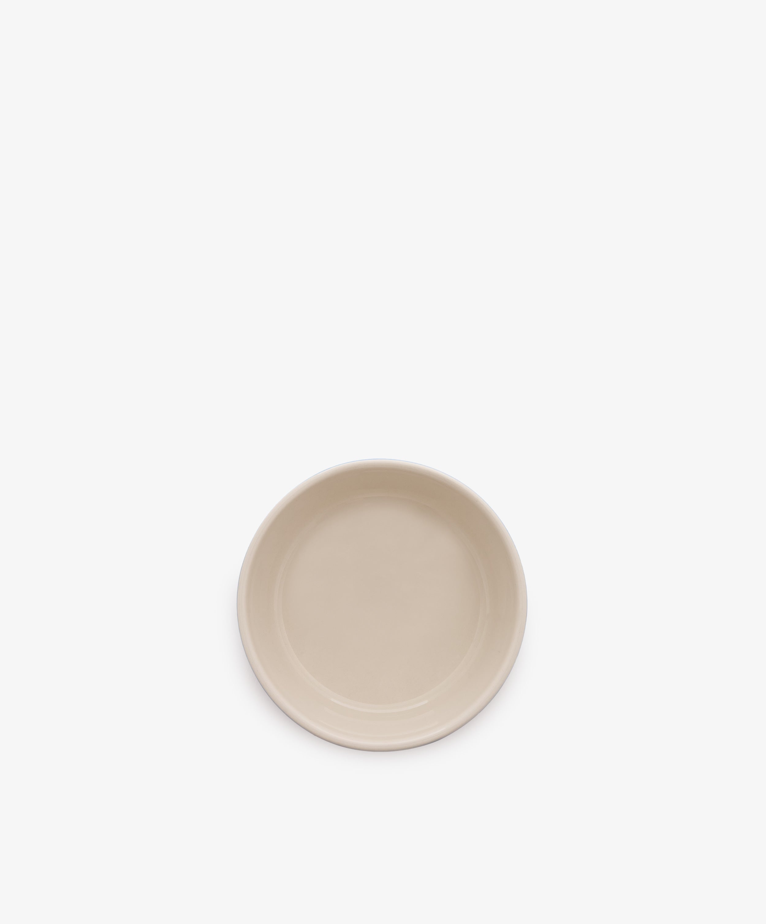 A plain, round, beige ceramic plate is centered on a white background, contrasting with a classic blue and white stripe dish like the Betty Dip Dish.
