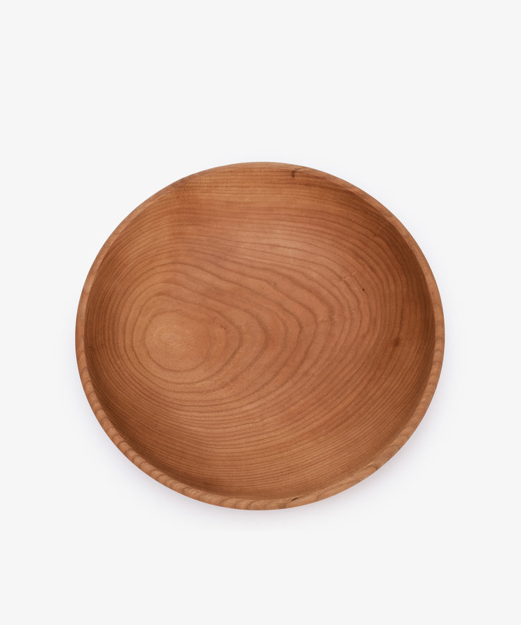 The August Wood Serving Bowl, a round and shallow handmade piece crafted from American dark cherry wood with a smooth finish, is shown from above on a plain white background.