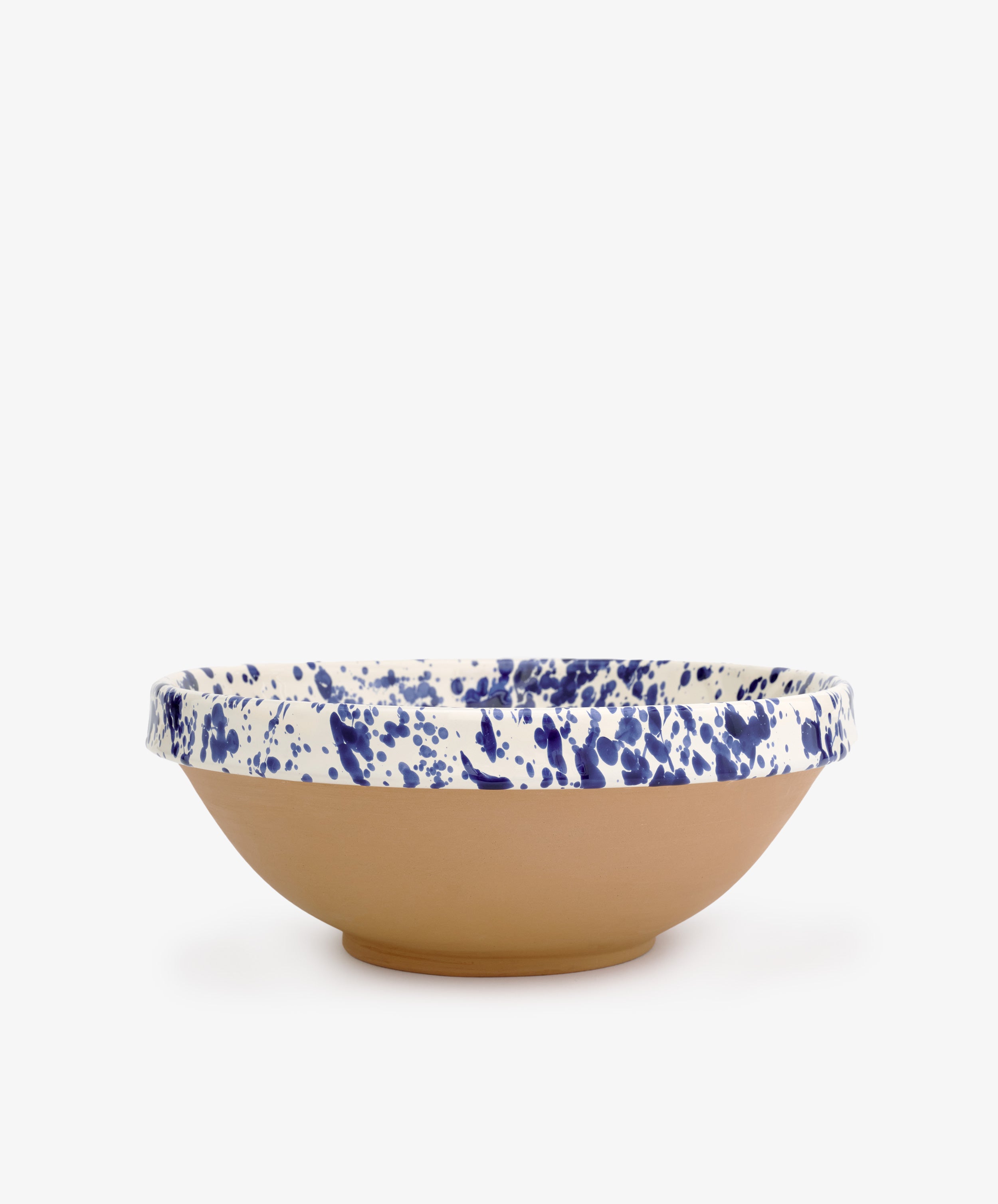 The Rita Bowl Splatter features a shallow, round design with a natural terracotta base and a white rim accented by blue splatter patterns, shown against a plain white background.