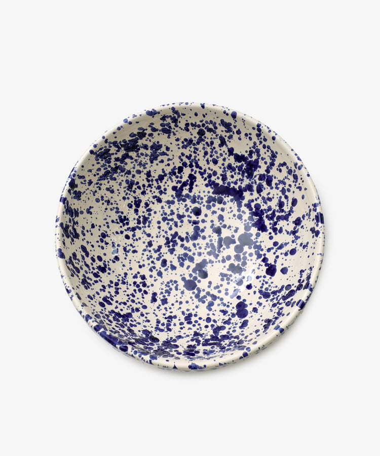 The Rita Bowl Splatter is a round ceramic bowl featuring a white base with a blue splatter pattern, shown from above against a plain background.