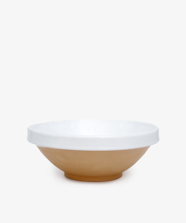 The Rita Bowl is a shallow glazed terracotta bowl with a tan base and white interior and rim, ideal for serving summer cherries or tomato salads. Photographed on a plain white background.