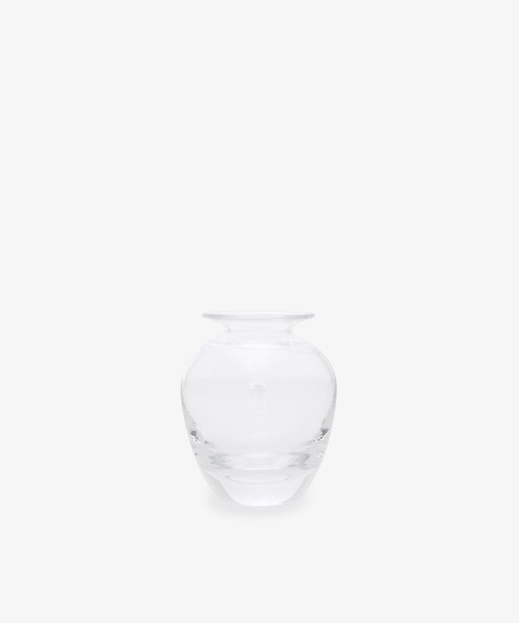 The Gem Bud Vase is a clear glass vase with a wide, round body and short, narrow neck, inspired by hand-blown bud vases from the South of France. It is showcased against a plain white background.