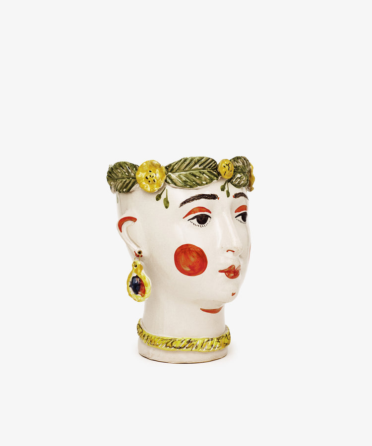 The Testa di Moro, Alfonsina is a sculptural ceramic vase shaped like a womans head with painted features, red cheeks, decorative earrings, a green wreath, and yellow flowers—an artistic addition to your homeware collection.