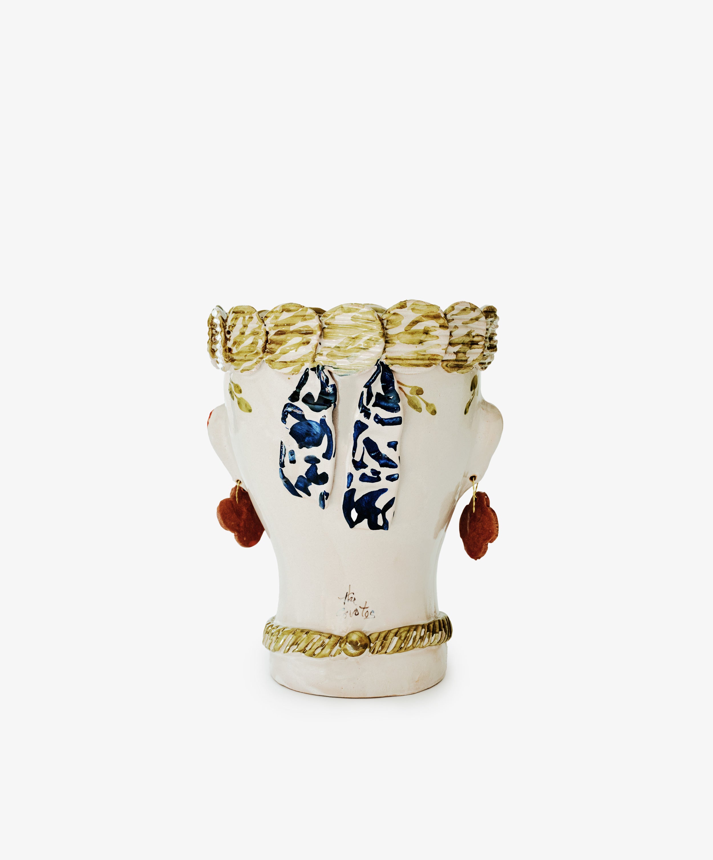 The Cabeza Recipiente, Biloba is a ceramic vase shaped like a human head with painted hair, earrings, and a scarf. This unique handmade decor piece is shown from the back against a plain white background.