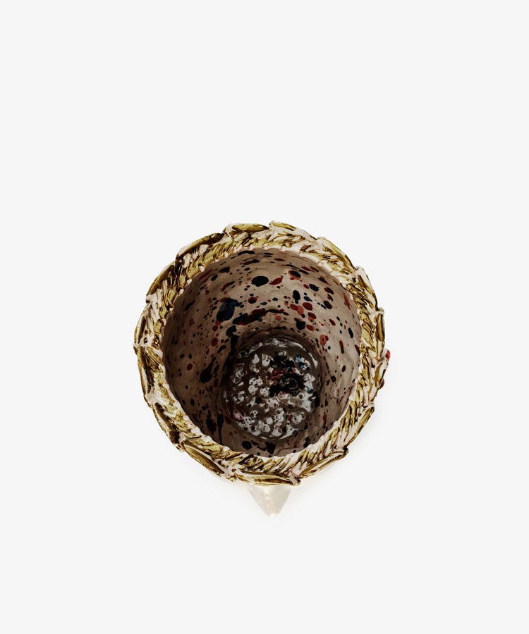 The Cabeza Recipiente, Biloba is a handmade ceramic cup with a textured gold rim and speckled interior, viewed from above against a white background—an elegant decor piece inspired by The Exvotos.