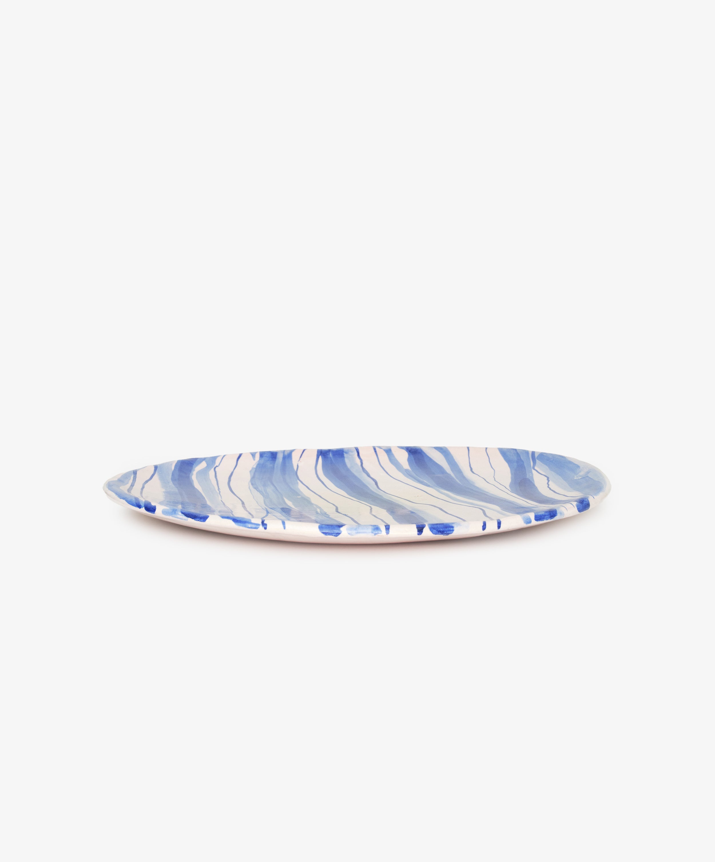 Banda Decorative Platter by The Exvotos. White and blue striped glazed ceramic platter, side view.