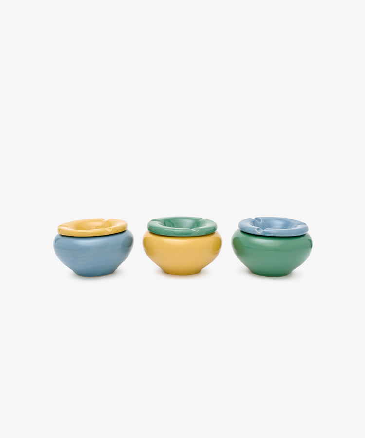 The Mix & Match Ashtray set features three small ceramic ashtrays in blue, yellow, and green, arranged in a row for a classic style that fits any space.