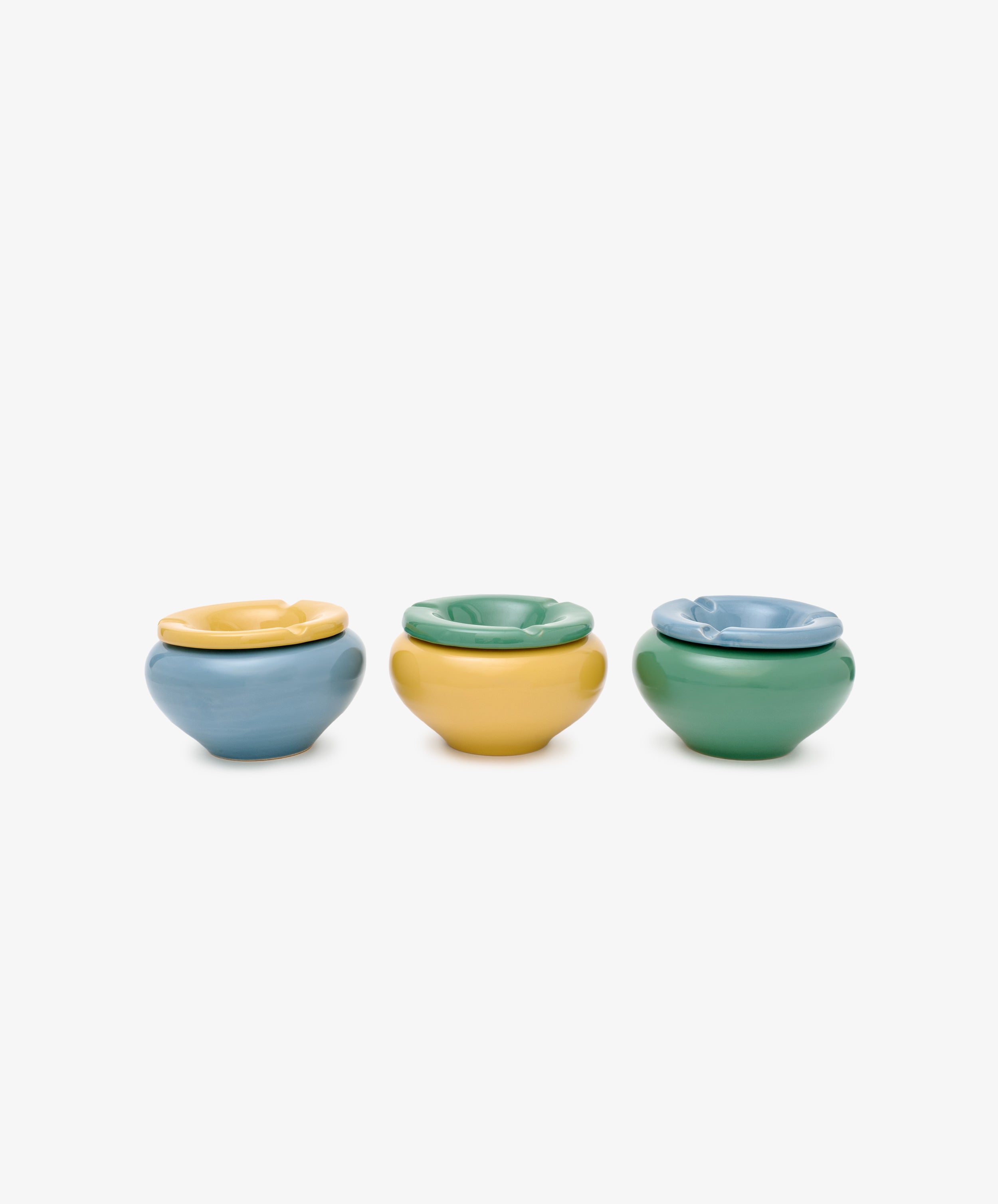 The Mix & Match Ashtray set features three small ceramic ashtrays in blue, yellow, and green, arranged in a row on a white background—ideal for bringing vintage charm to any space.