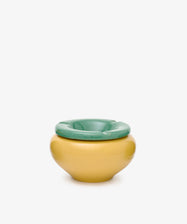 The Mix & Match Ashtray, featuring playful yellow and green hues in chunky ceramic, sits against a plain white background—its design evoking the whimsical forms of childhood objects, handmade in Italy.
