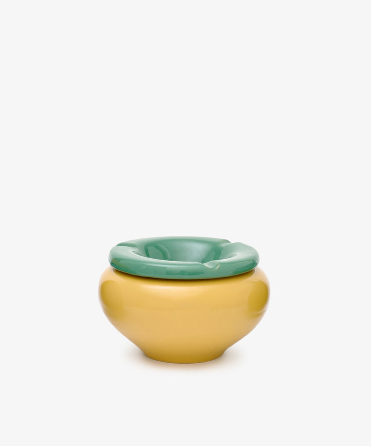 The Mix & Match Ashtray, featuring playful yellow and green hues in chunky ceramic, sits against a plain white background—its design evoking the whimsical forms of childhood objects, handmade in Italy.