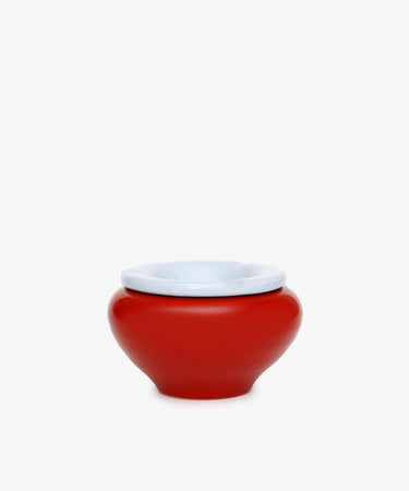 The Mix & Match Ashtray is a chunky, handmade ceramic piece from Italy, featuring a red, round shape with a white rim and displayed on a plain white background.