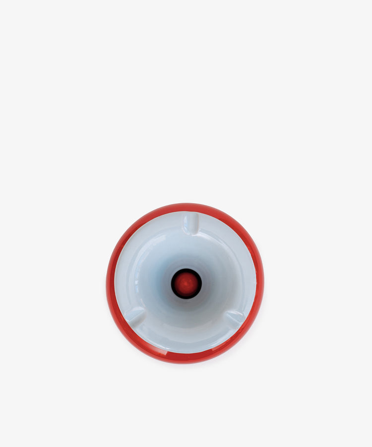 A top-down view of the Mix & Match Ashtray, a chunky white ceramic piece with a red rim and central red accent, handmade in Italy and placed against a plain white background.